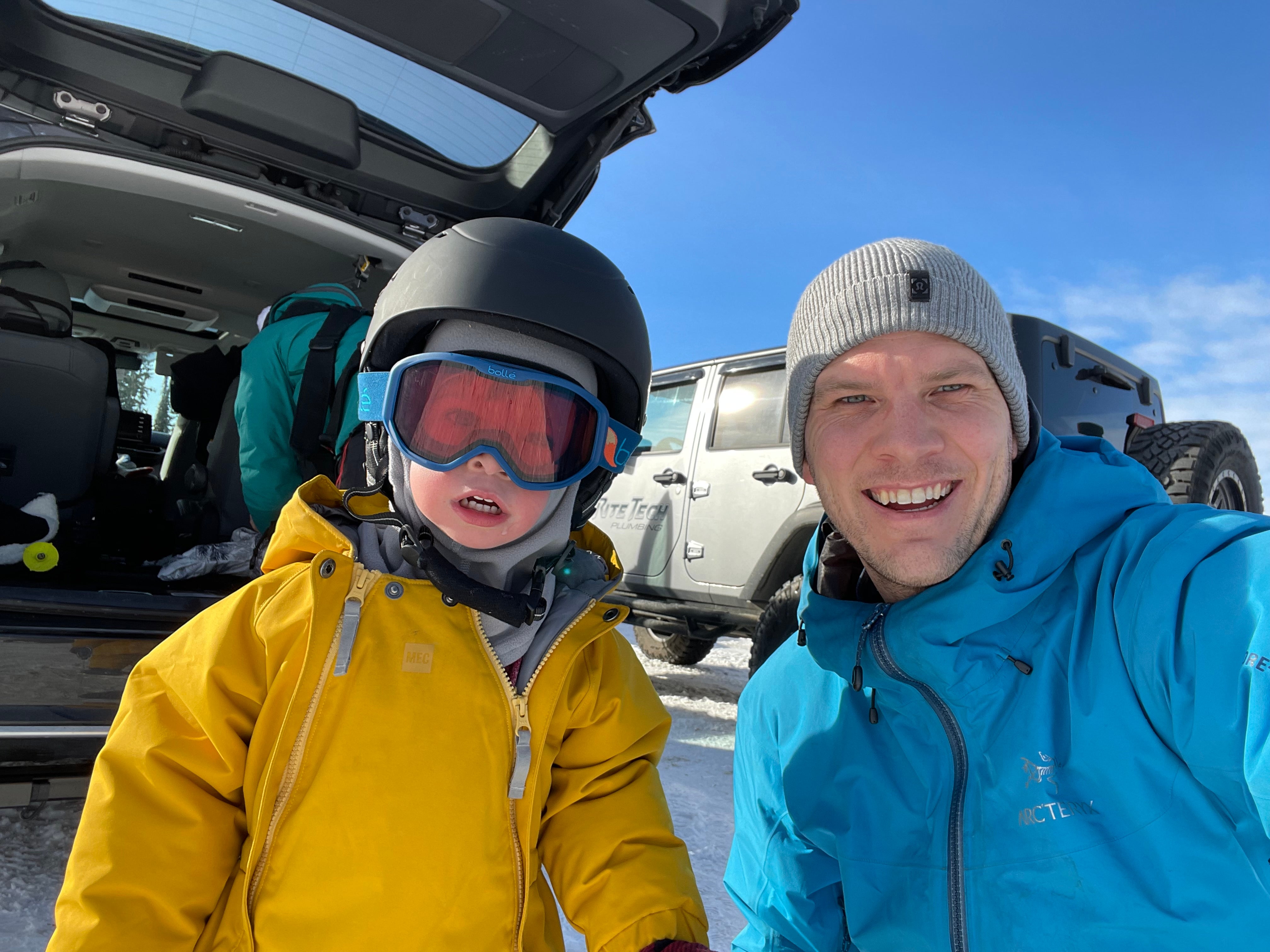 A man and a child with a ski helmet in winter jackets.