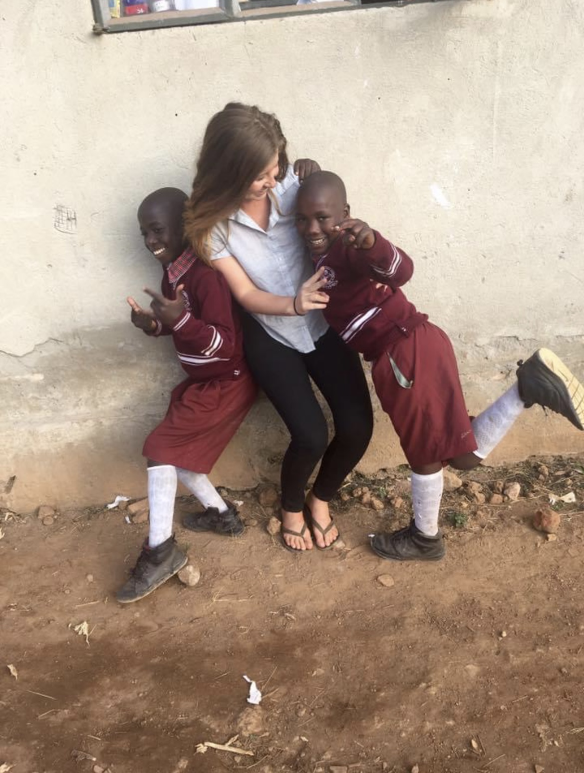 Young woman playing with two boys who are wearing their school uniforms