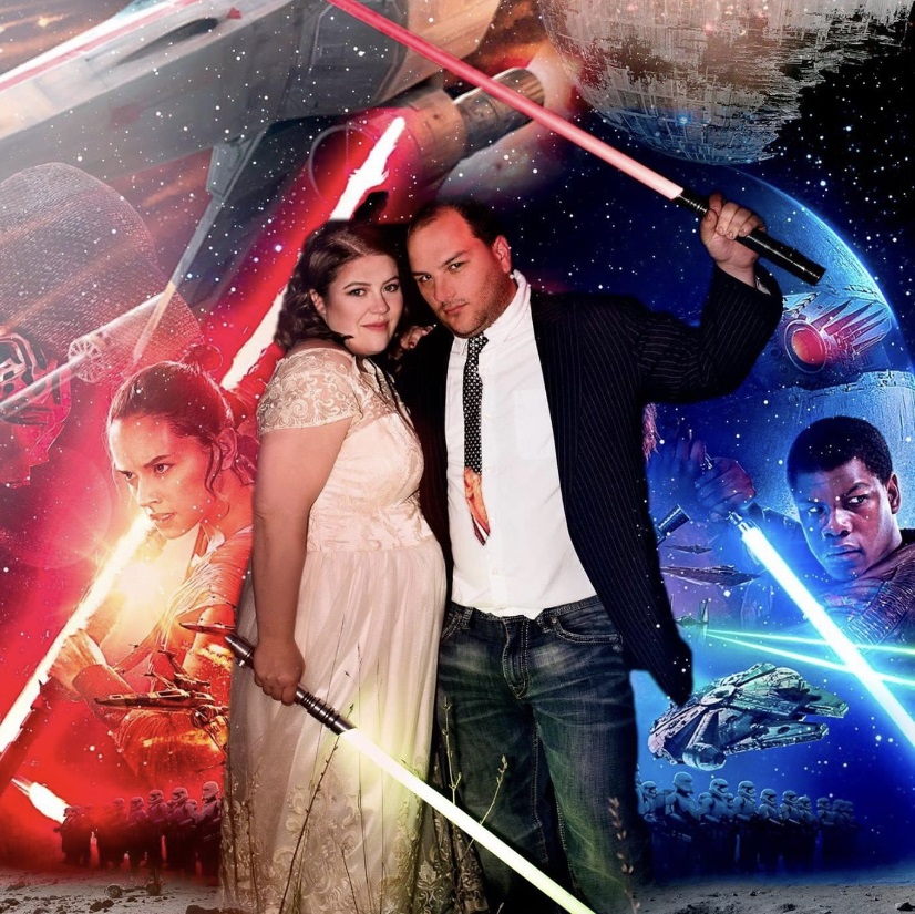 a woman and man are married dressed as Jedi’s holding lightsabers against a Star Wars-themed background