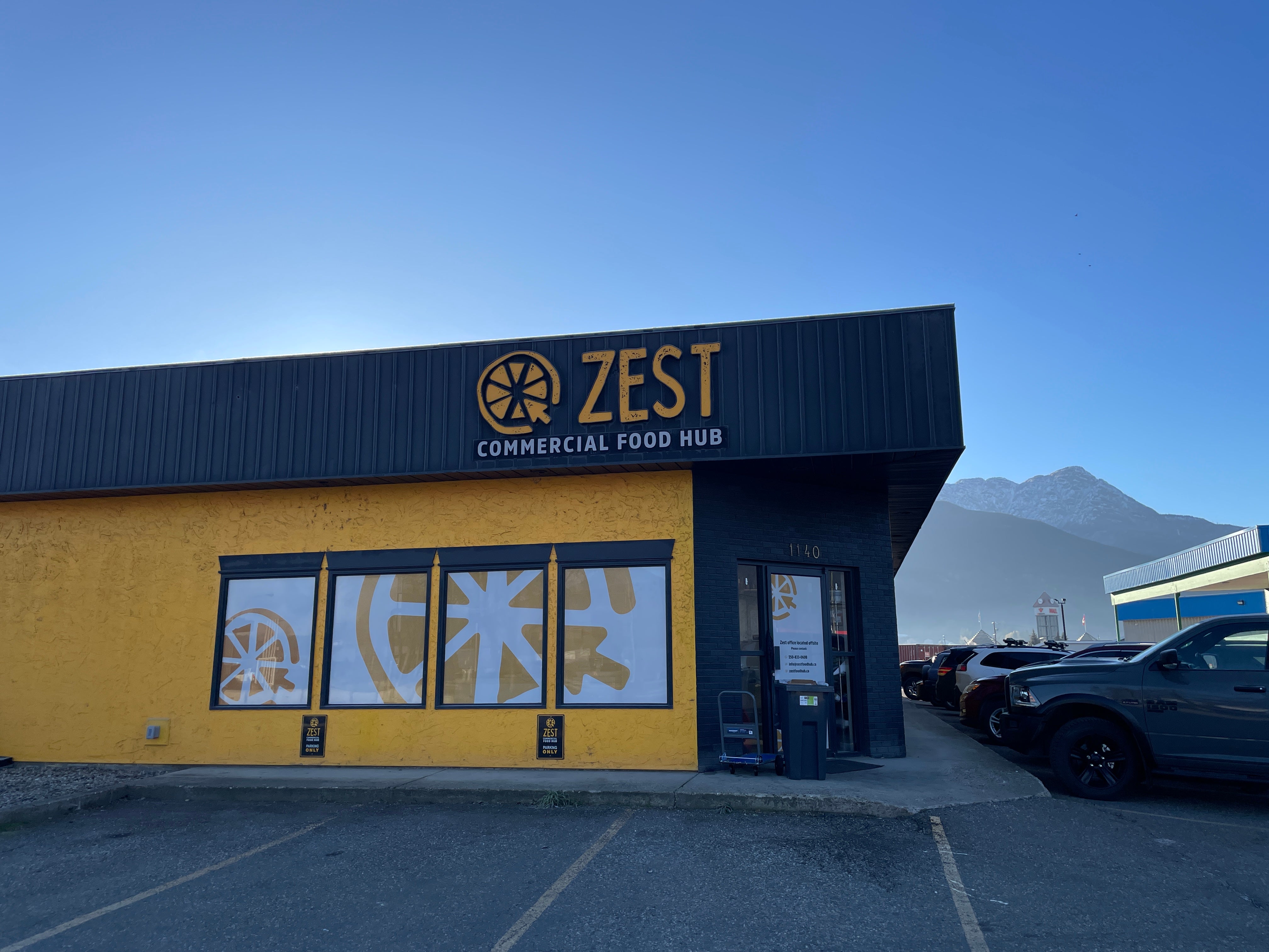 a yellow and grey building that has parking lot stalls surrounding it