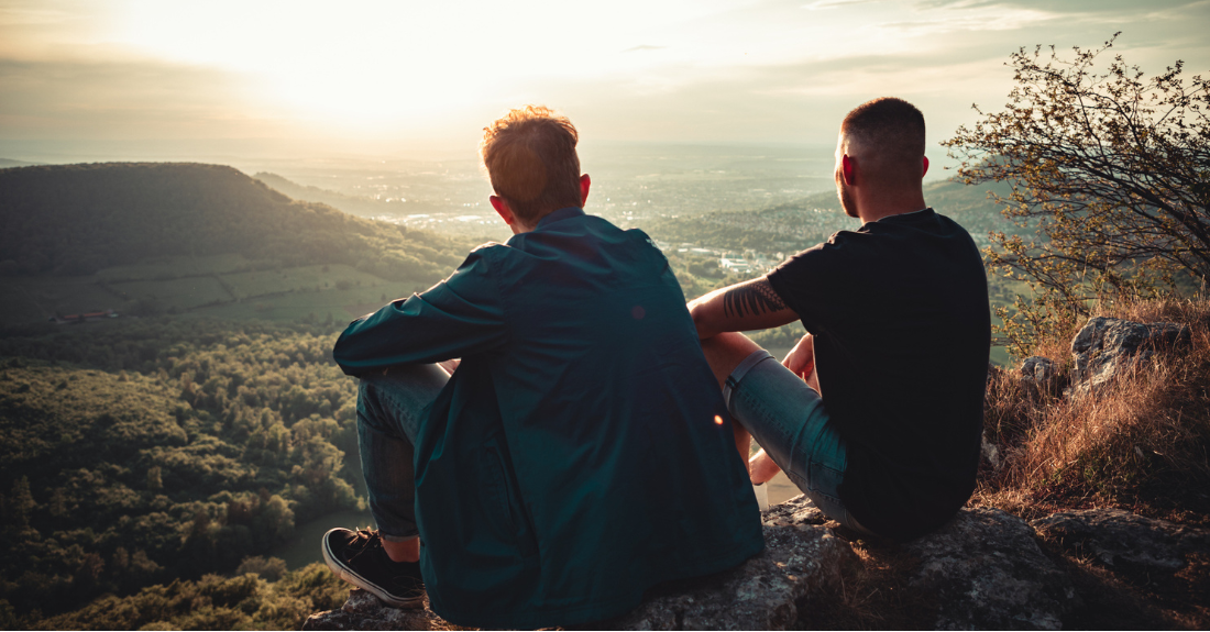 Two teens stare at sunset.