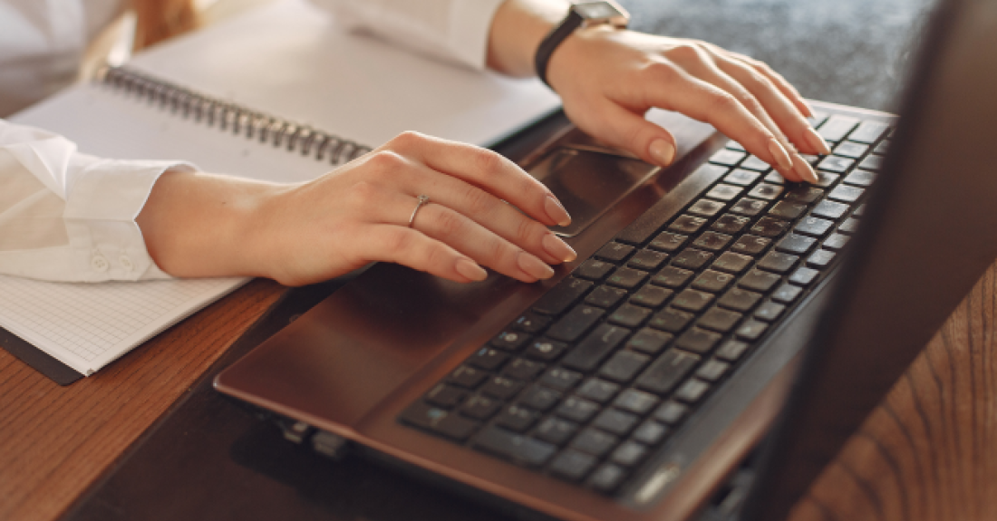 Hands typing on a laptop keyboard