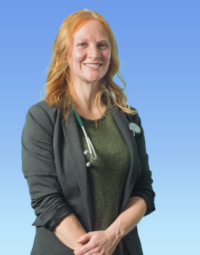 A profile shot of a woman with amber hair wearing a green shirt with a grey suit jacket over top and a stethoscope over one shoulder.