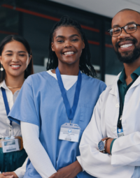 Three smiling people wearing medical attire.