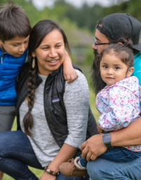 Two adults and two children kneeling in grass.