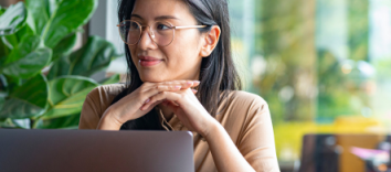 Woman smiles as she sits behind her laptop