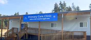 A long, horizontal building with wooden stairs and a ramp, with a sign reading Primary Care Clinic.