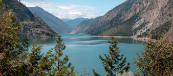 A nature scene featuring a large body of water surrounded by mountains and trees.