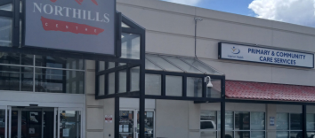 A strip mall with a large sign that says Northills Centre and a smaller sign to the right with the Interior Health logo and text reading Primary &amp; Community Care Services.