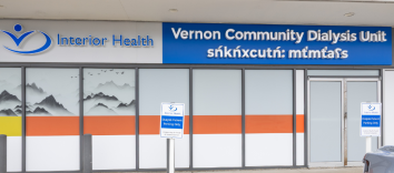 The exterior of a building with a large Interior Health logo on the wall next to a sign reading Vernon Community Dialysis Unit.