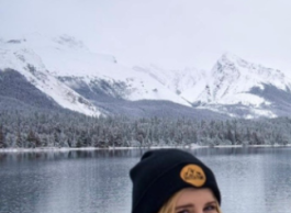 Woman in front of snowy mountains and lake.