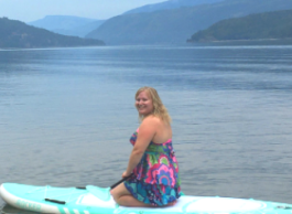 Woman sitting on paddleboard on lake.