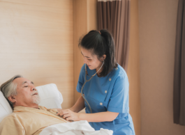 A health-care professionals tend to a patient who's lying in bed.