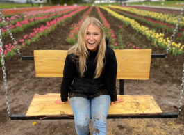 Laughing young woman sitting on a bench in a tulip field.