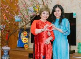 Two individuals pose for a photo in traditional Vietnamese gowns.