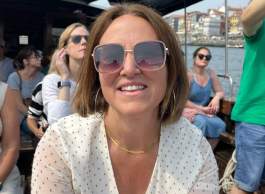 Woman with short hair wearing sunglasses and polka dot dress on riverboat.