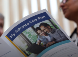 a healthcare practitioner with a senior looking through a booklet on advance care planning