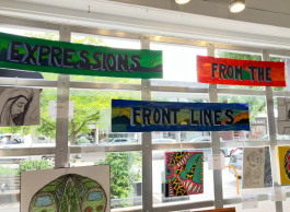 A window display of colourful art titled Expressions from the Front Lines.