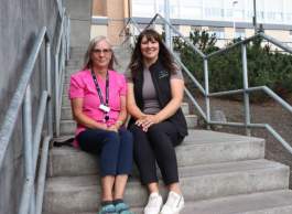 Two people sitting outside together on concrete steps.