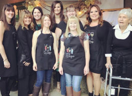 A group of 9 people in black aprons that say Sip Happens.
