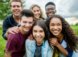 group of smiling youth outside in grassy area
