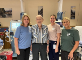 A group of four people stand together. Behind them, you can see monitors and hospital beds.