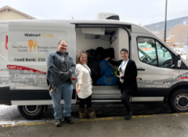 people standing outside of a truck putting donations into it.