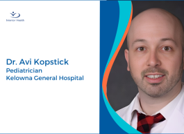 A headshot of a person with a bald head and light facial wear wearing a white shirt and red tie.