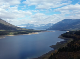 A river in a valley with blue sky and clouds overhead.