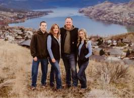 Four family members standing on a hillside overlooking a lakeside community and lake.