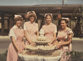 Four teenagers wearing red-and-white-striped uniforms standing outside by a fountain.