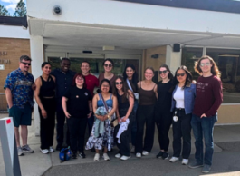 A happy group of people outside a hospital on a sunny day.