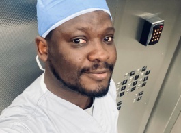 Person wearing scrubs and a surgical cap posing for a photo inside an elevator.
